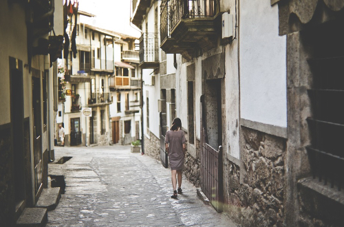 A woman walking along the narrow street of the town.